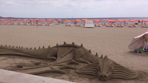 Una playa con hileras de sombrillas anaranjadas y sillas reclinables blancas.