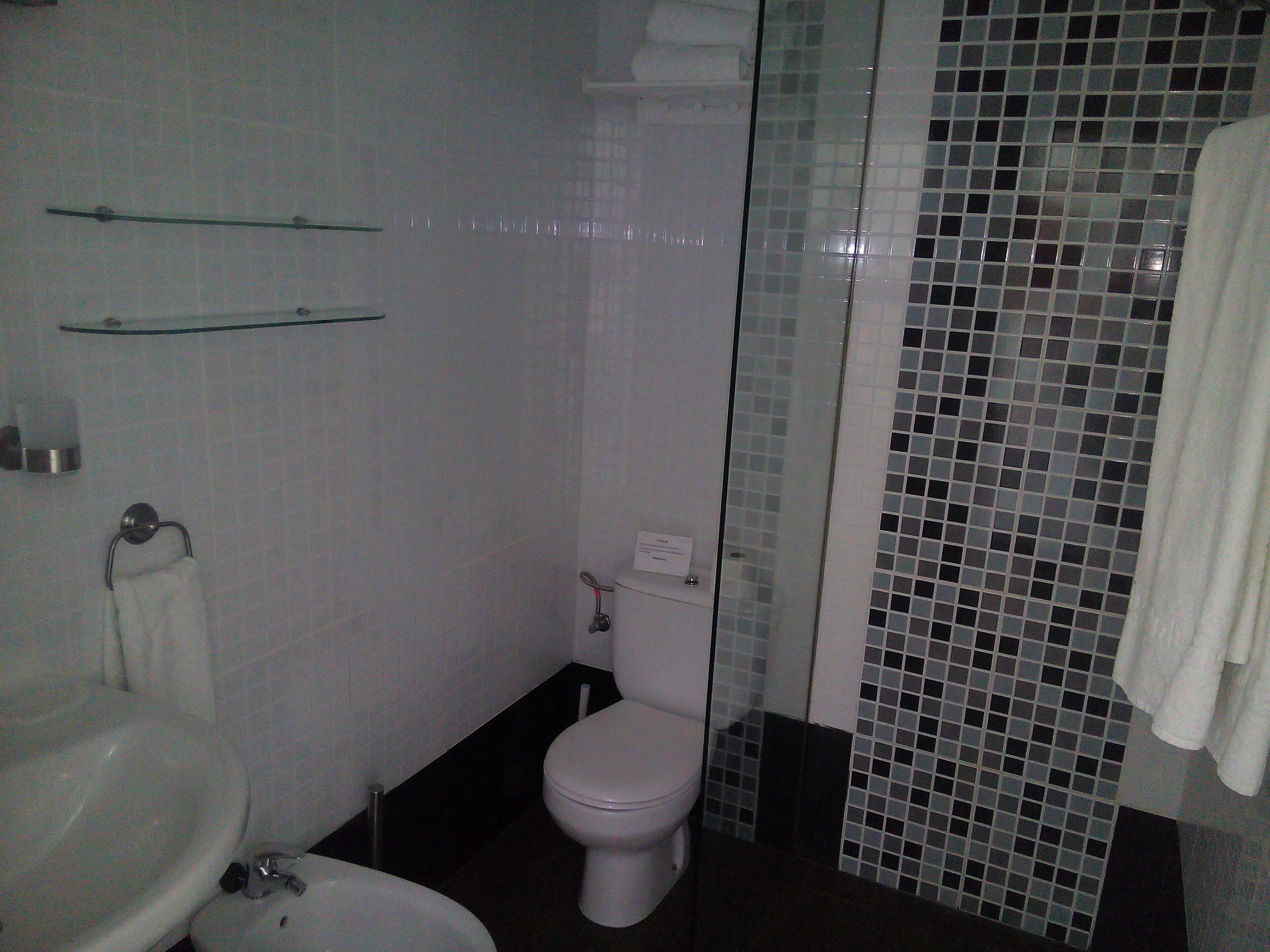 Un baño con inodoro, lavamanos y cabina de ducha de vidrio.