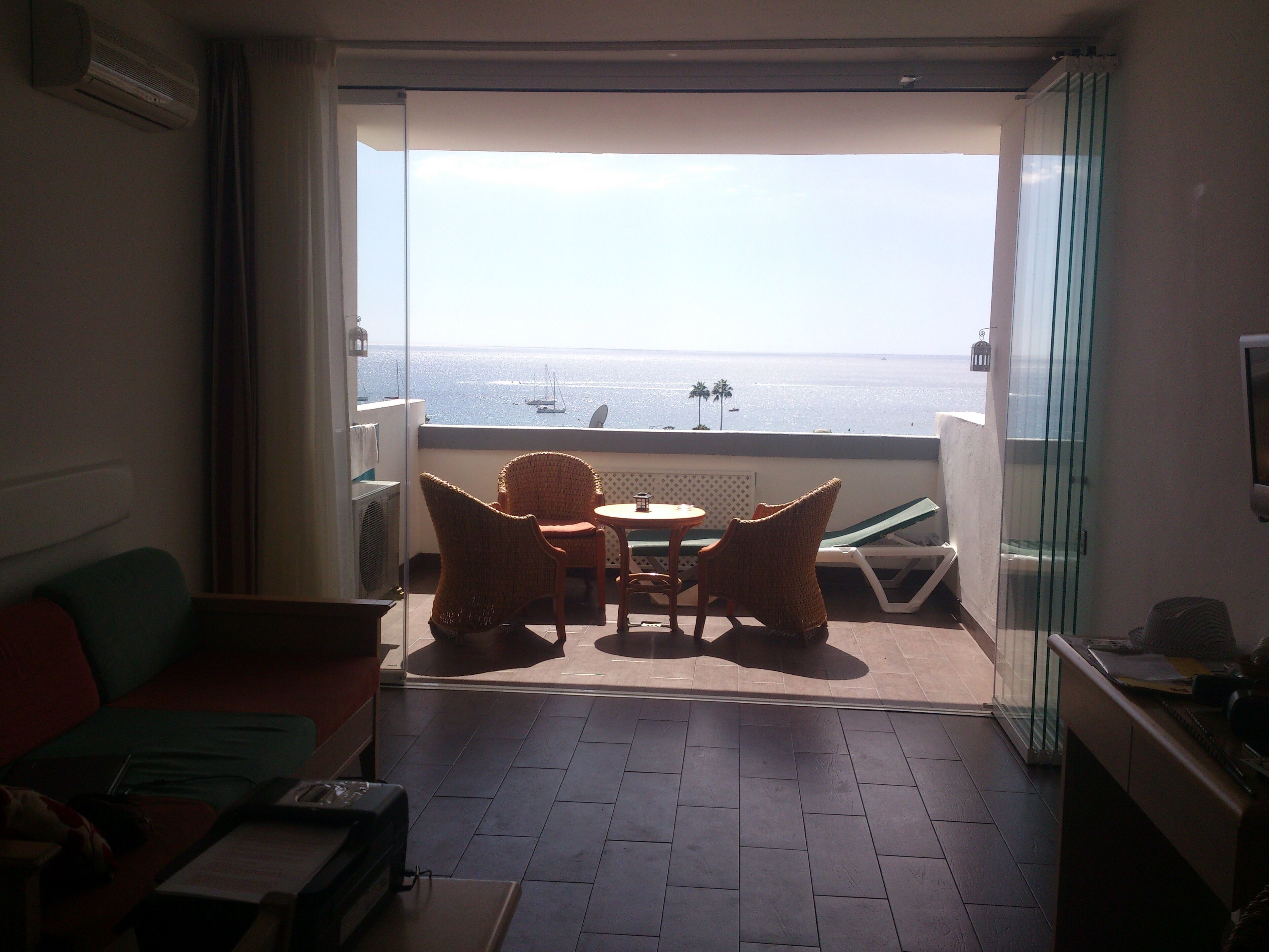 Ein Balkon mit Meerblick, Korbstühle, ein kleiner Tisch und eine Couch.