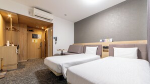 A hotel room with two beds, a wooden wardrobe, a small table, and a wall-mounted phone.
