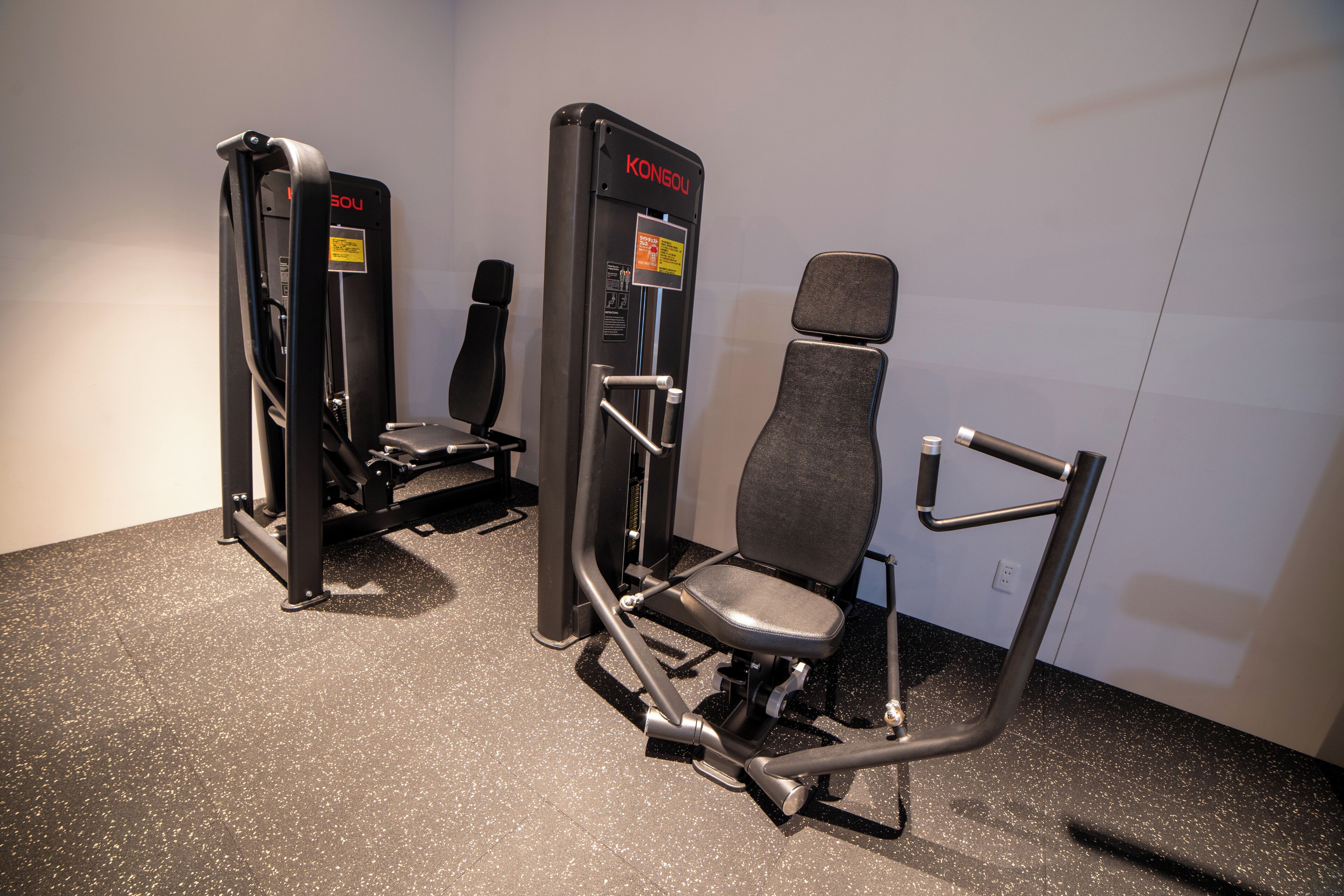A gym with two KONGOU machines and a chair.