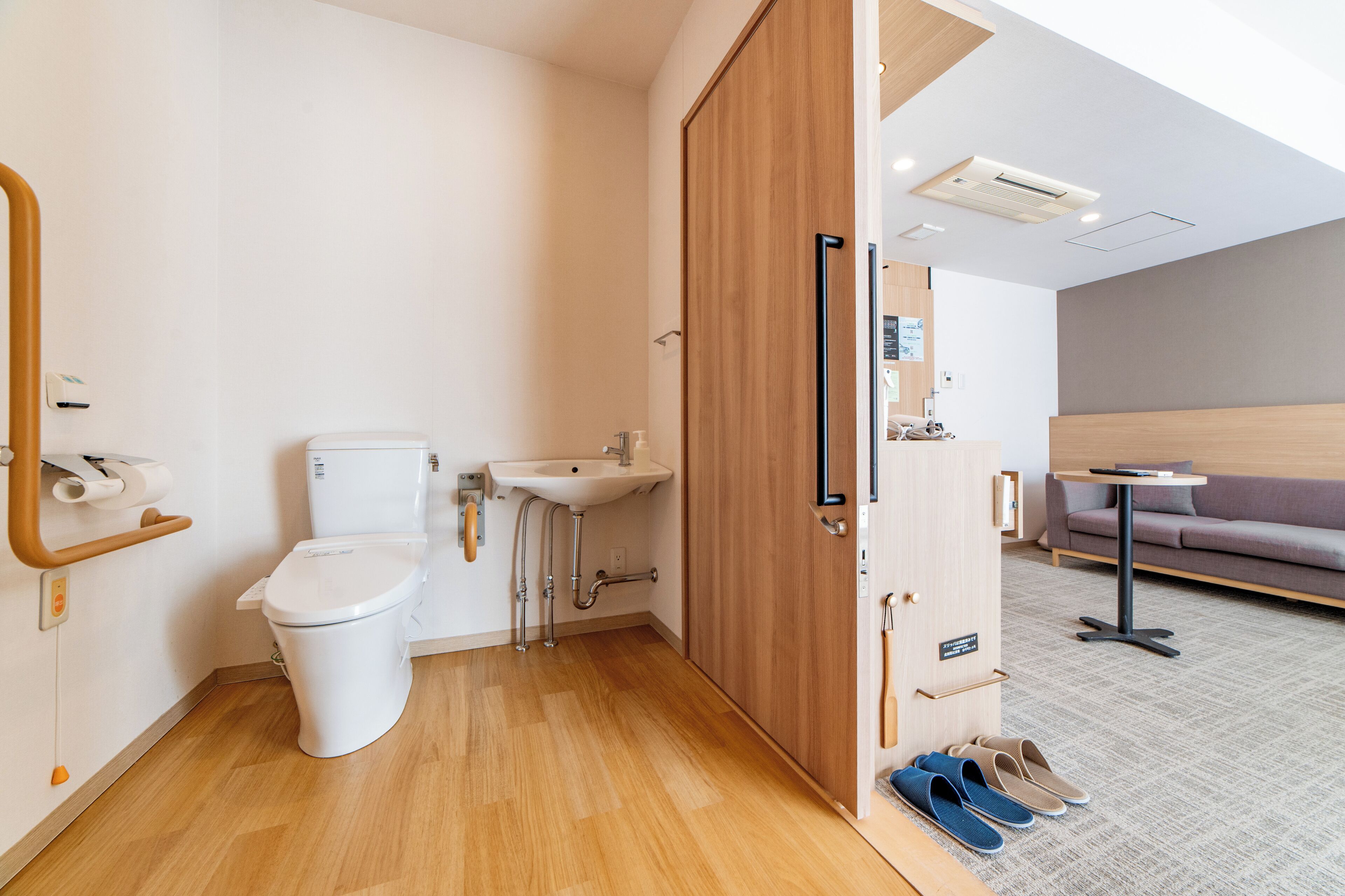 A modern bathroom with a toilet, sink, and wooden door.
