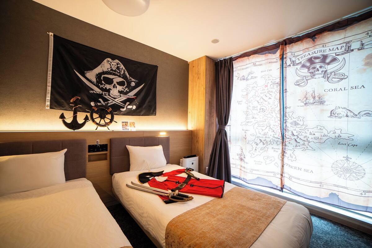 A hotel room with two beds, a map on the wall, and a treasure map on the window.