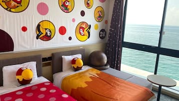 Ein Hotelzimmer mit Bett, Kissen, einem runden Tisch und einem großen Fenster mit Meerblick.
