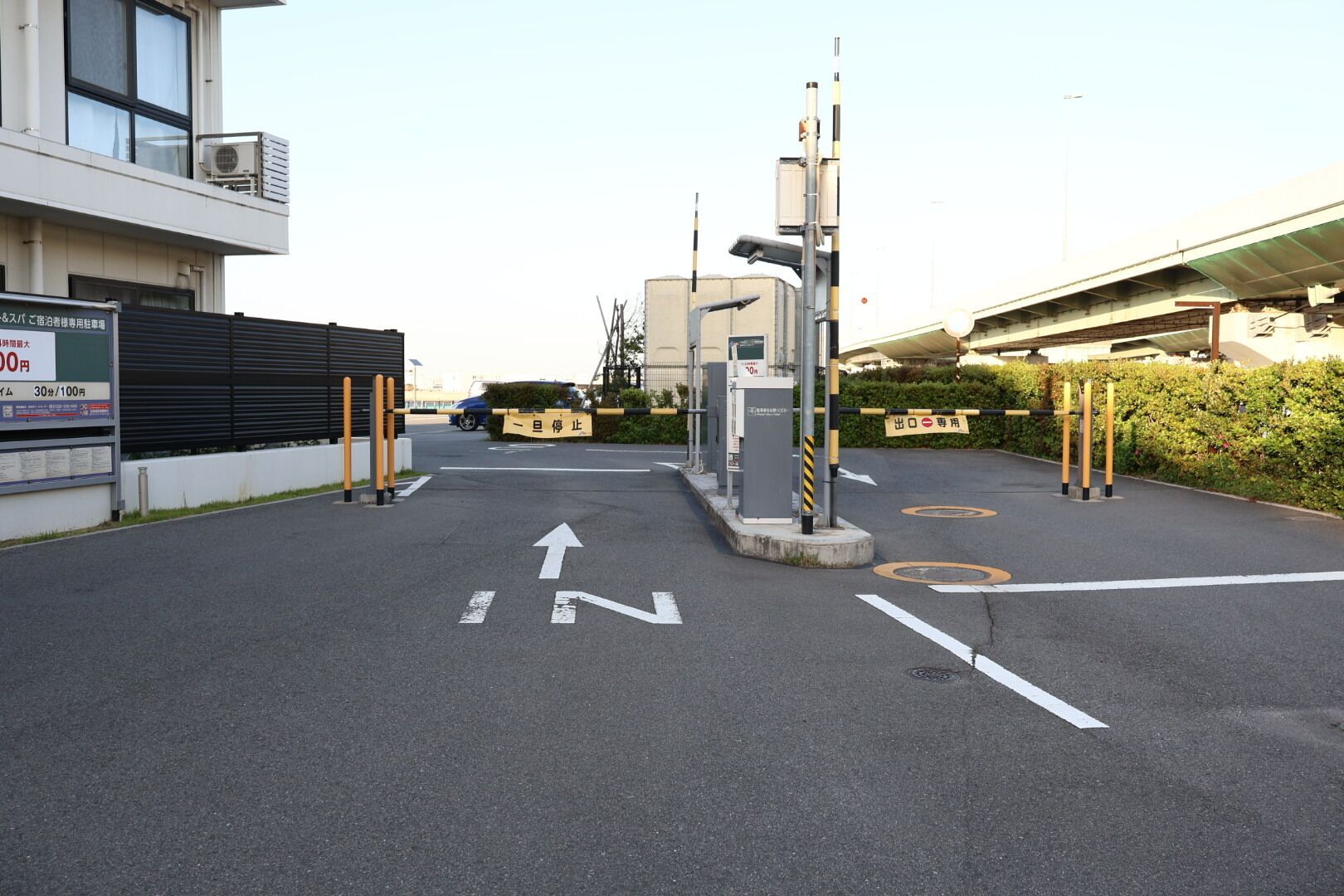 Ein Parkplatz mit Pfeilen, einer Schranke und einem Gebäude mit einem Schild.