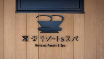 A wooden wall with a sign for Henn na Resort & Spa.