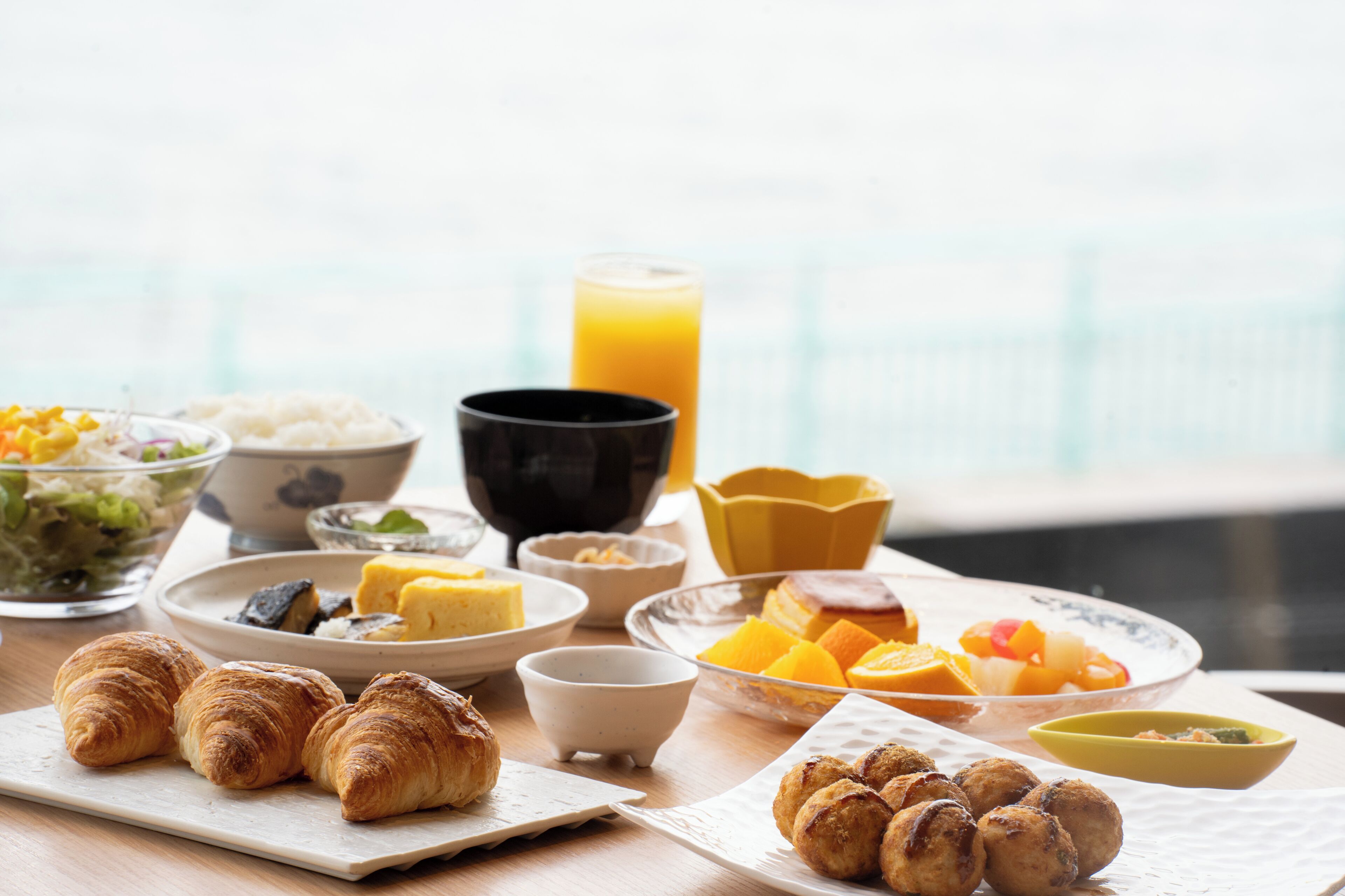 A breakfast table with croissants, fruit, and a glass of orange juice.