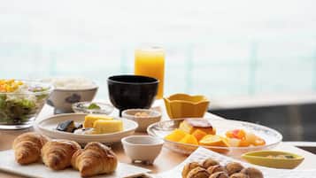 A breakfast table with croissants, fruit, and a glass of orange juice.