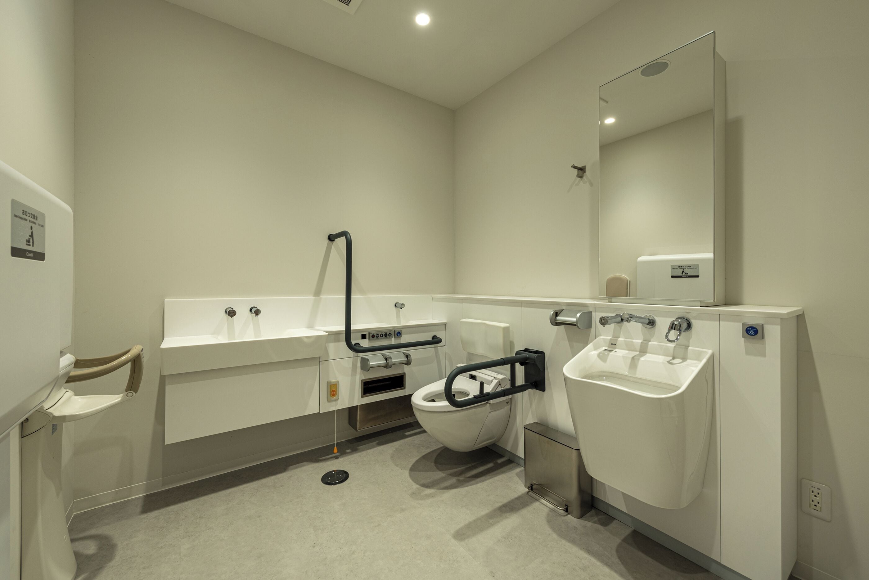 A modern bathroom with a toilet, two sinks, and a mirror.