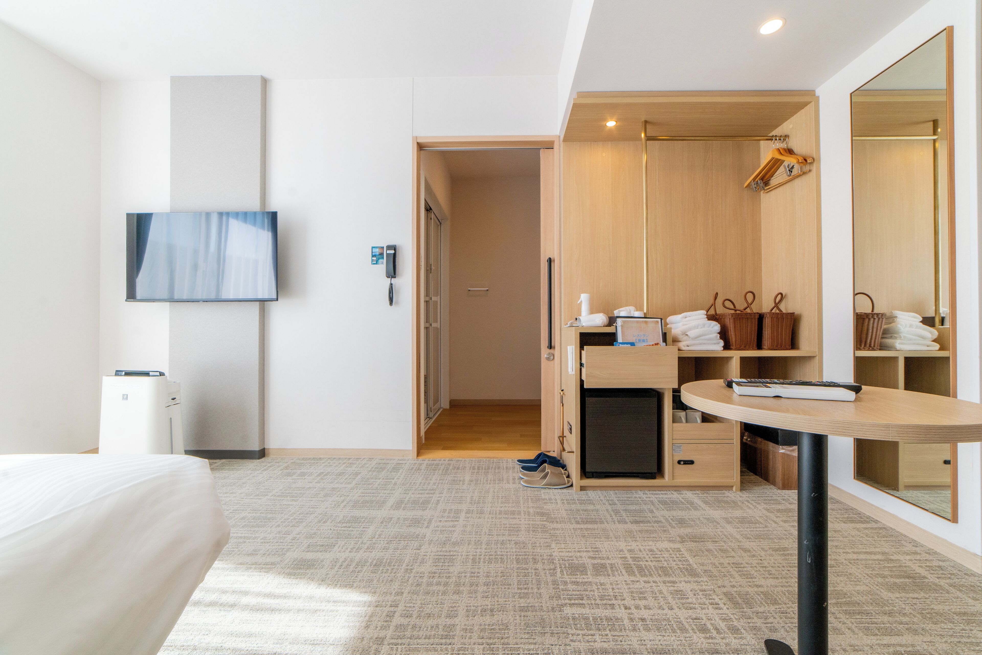 Una habitación de hotel moderna con cama, escritorio, espejo, televisor, armario y baño.