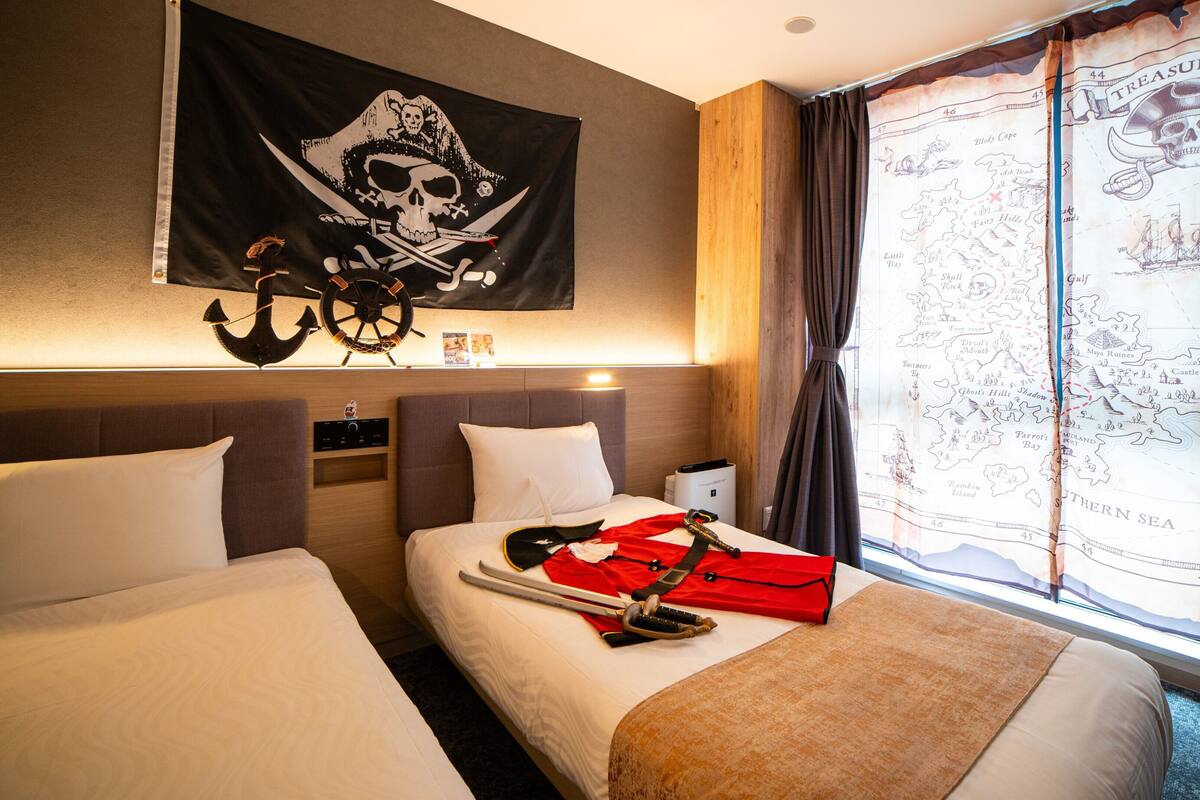 A hotel room with two beds, a map of the Caribbean on the wall, and a pirate-themed flag.