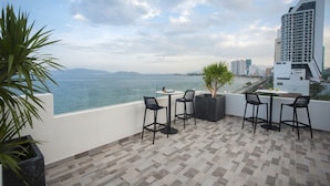 Une terrasse avec vue sur la mer, comprenant une table et des chaises, un pot de fleurs et un sol carrelé.
