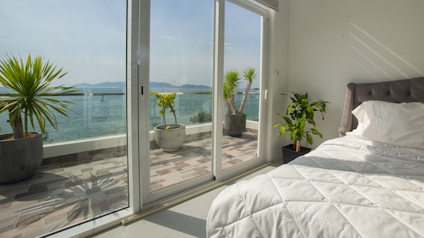 Une chambre dotée d’une grande porte-fenêtre coulissante donnant sur un balcon avec vue sur la mer.