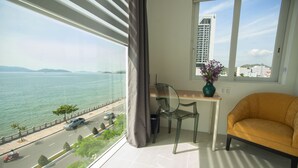 Un balcon avec vue sur la mer, une chaise, une table et un vase rempli de fleurs.