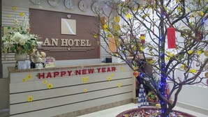 A hotel reception desk with clocks displaying different cities, a 'Happy New Year' sign, and a decorative tree with lights. - An Hotel Can Tho (Can Tho)