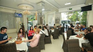 A restaurant with wicker chairs and tables, a chandelier, and a TV on the wall. - An Hotel Can Tho (Can Tho)