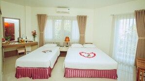 A hotel room with two beds, a desk with a chair, a lamp, and a mirror. - An Hotel Can Tho (Can Tho)