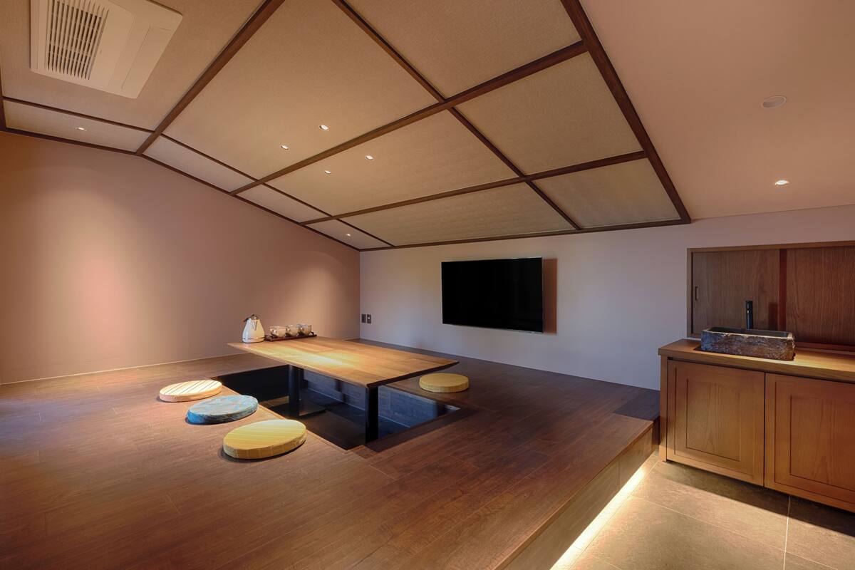 Ein modernes Interieur mit einem Holzespeisetisch, gepolsterten Sitzmöglichkeiten, einem Flachbildfernseher und einer Holzkabine.