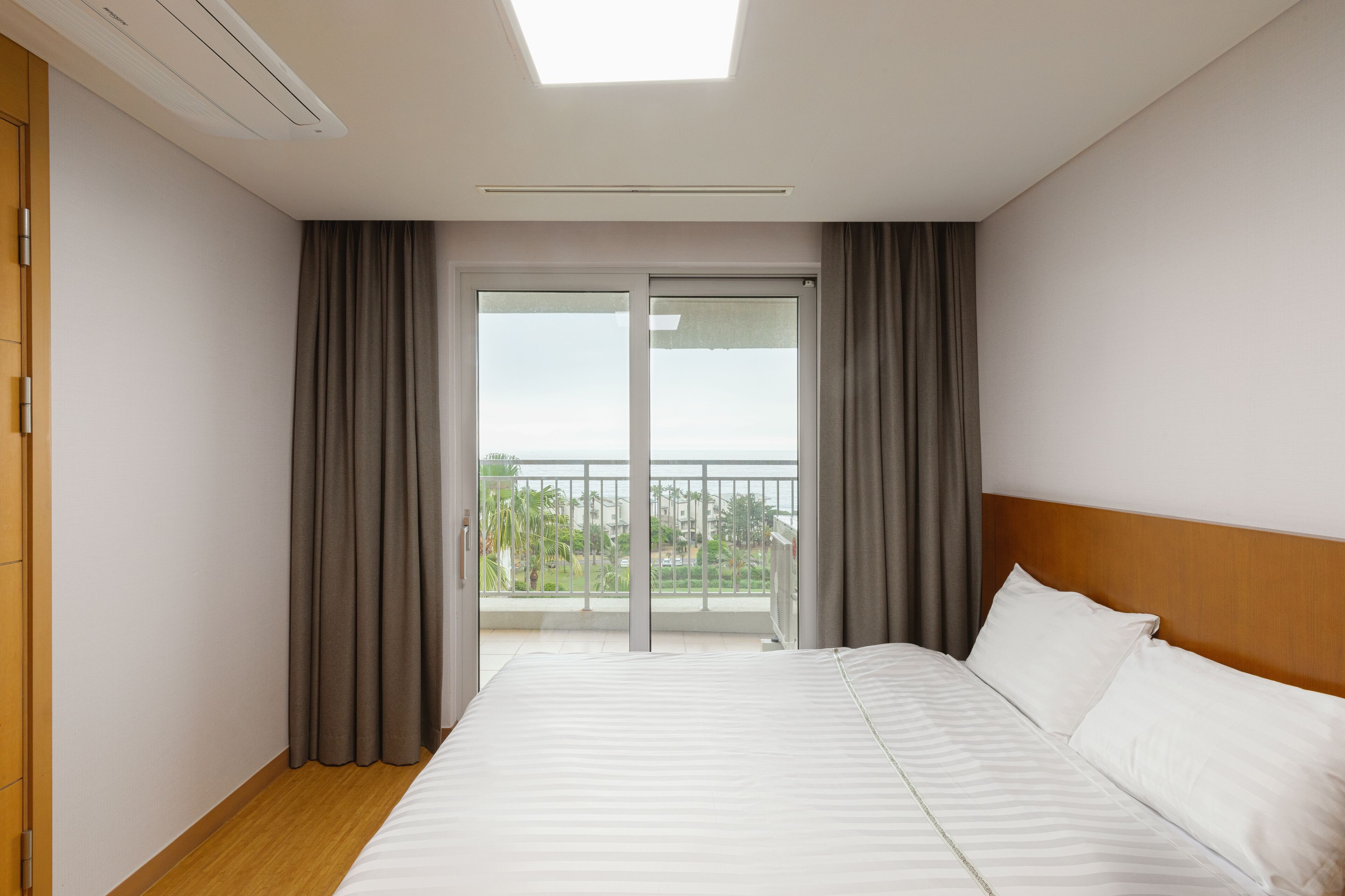 A hotel room with a large bed, a skylight, and a balcony with curtains.