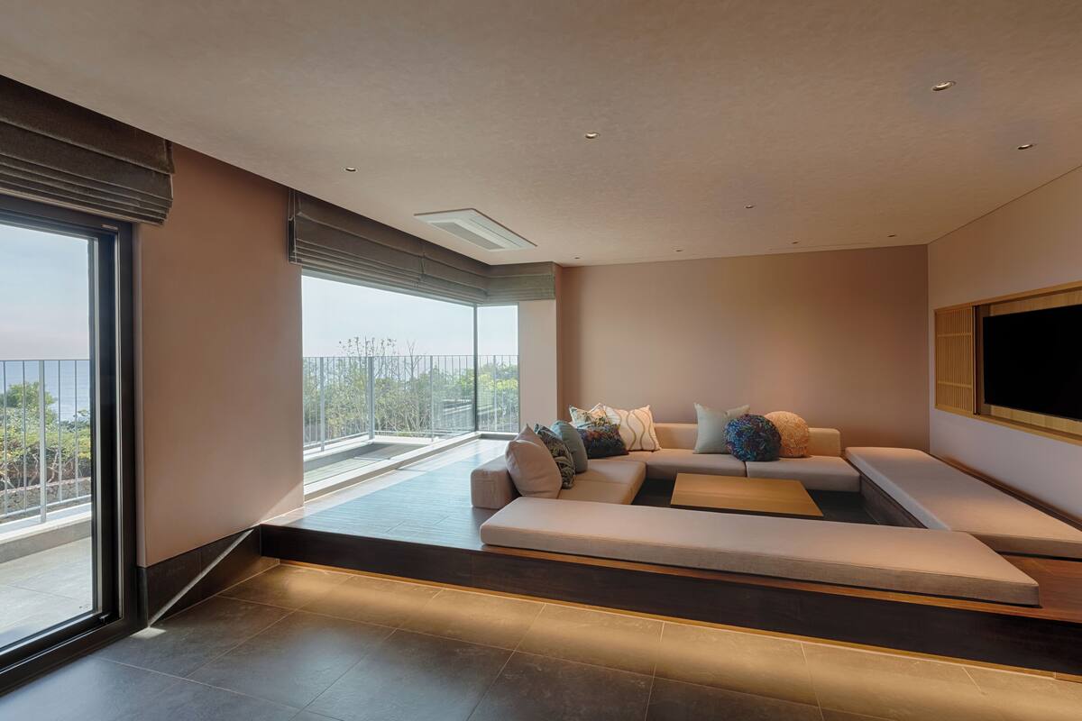 Ein modernes Wohnzimmer mit großem Fenster, einem modularen Sofa und einem Flachbildfernseher.