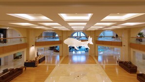 A spacious lobby with a high ceiling, skylights, and a central hanging sculpture. - Sono Calm Jeju (Seogwipo)