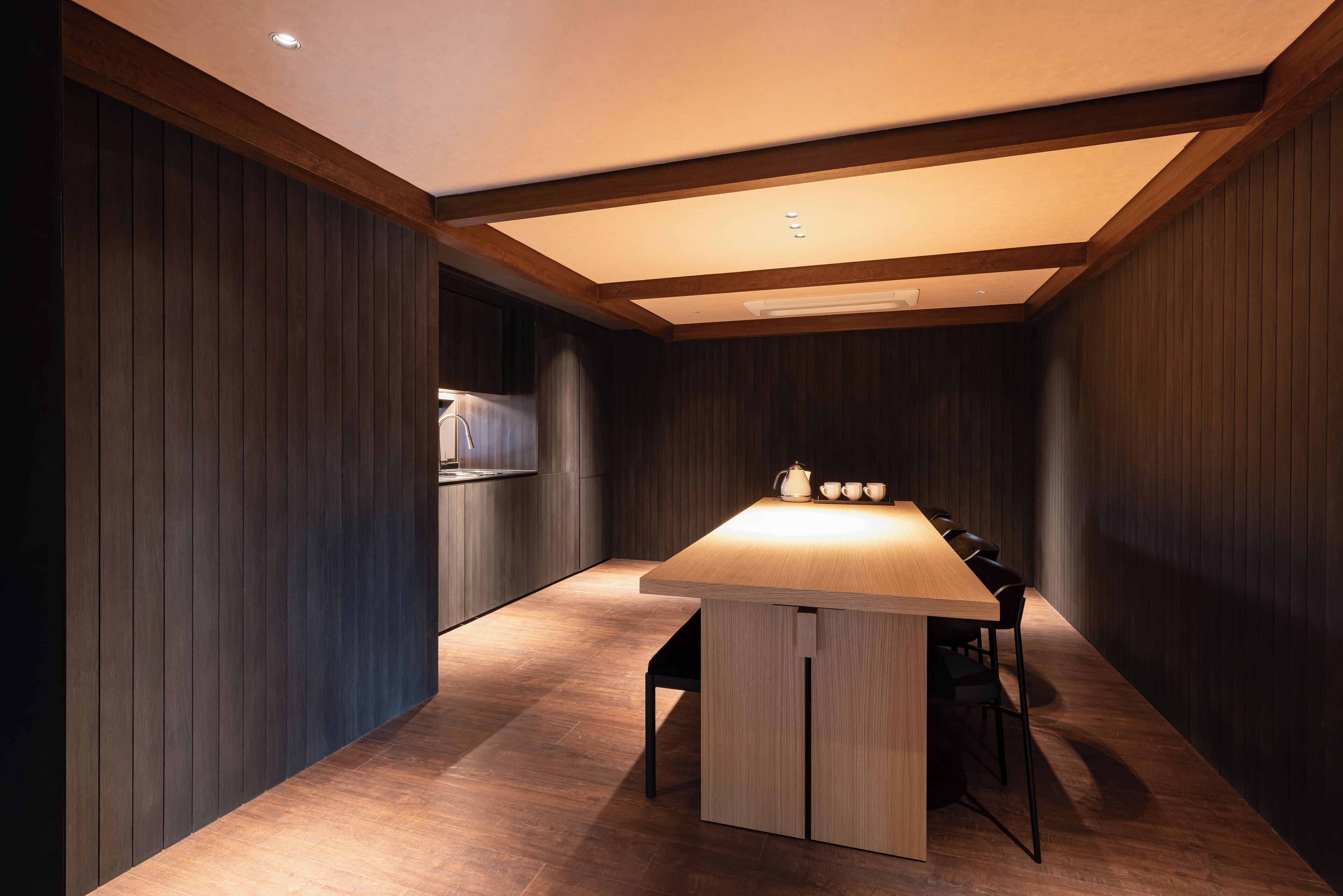 A modern kitchen with wooden cabinets, a central island with seating, and recessed lighting.