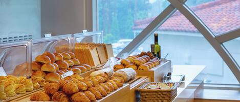 A bakery display with various baked goods and a bottle of olive oil.