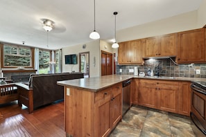 A kitchen with wooden cabinets, a stone backsplash, and a built-in island. - Incredible ski in/ski out location SX# 37 (EV charger) (Sun Peaks)
