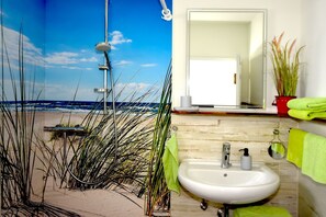 A bathroom with a beach mural, a sink, and a shower. - Beach house B - Deichoase beach house (Friedrichskoog)