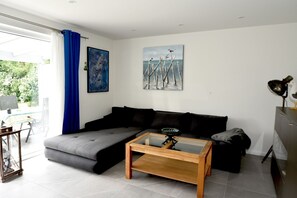 En moderne stue med en grå hjørnesofa, et glasbord og kunst på væggene.