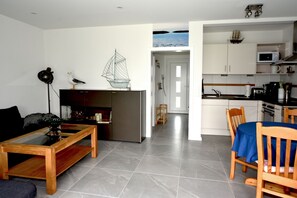 Una sala de estar moderna con una mesa de centro de cristal, un sofá de madera y una pequeña decoración de velero sobre un mueble.