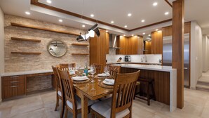 A modern kitchen with wooden cabinets, a central island, and a dining area with chairs and a table set for a meal.