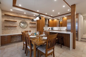 A modern kitchen with wooden cabinets, a central island, and a dining area with chairs and a table set for a meal.