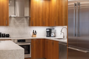 A modern kitchen with wooden cabinets, stainless steel appliances, and a marble countertop.