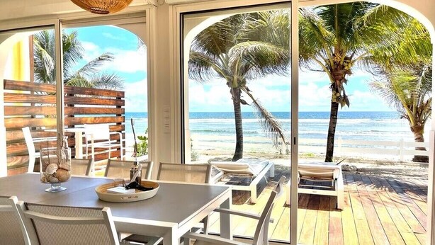 A dining area with a view of the beach and ocean through large windows. - Red coral, feet in the sand (Saint-François)