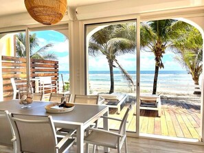 A dining area with a view of the beach and ocean through large windows. - Red coral, feet in the sand (Saint-François)