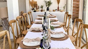 A dining table set with wooden chairs, white tablecloth, and centerpieces including candles and greenery. - Red coral, feet in the sand (Saint-François)