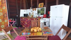 A cozy kitchen with a wooden table, chairs, and a refrigerator. - duplex apartment on two floors with panoramic sea views (Le Moule)