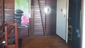 A wooden staircase leading to a room with a mirror, a poster of flowers, and a small stool near a door. - duplex apartment on two floors with panoramic sea views (Le Moule)