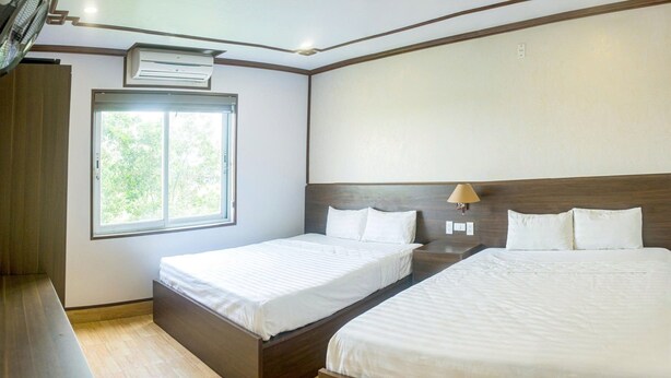 A hotel room with two beds, a window, an air conditioning unit, and a bedside lamp. - Anh Duong Hotel (Hanoi)