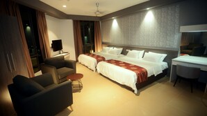 A hotel room with two beds, a desk, a chair, a sofa, and a TV. - Star Well Hotel (Kuala Lipis)