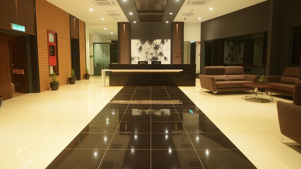 A modern hotel lobby with a reception desk, seating area, and potted plants. - Star Well Hotel (Kuala Lipis)