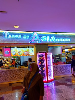 A brightly lit food court with a neon sign reading "TASTE OF ASIA FOOD COURT". - KL Times Square Residence (Kuala Lumpur)