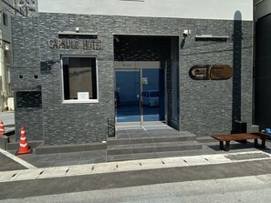 The exterior of a hotel with a stone facade, a glass entrance, and a bench outside.
