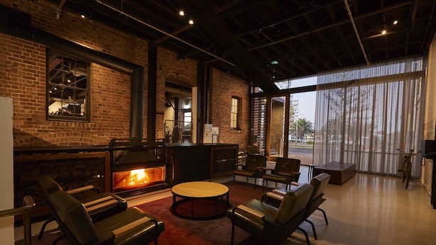 A modern lounge area with leather chairs, a central coffee table, and a fireplace. - Premier Mill Hotel (Katanning)