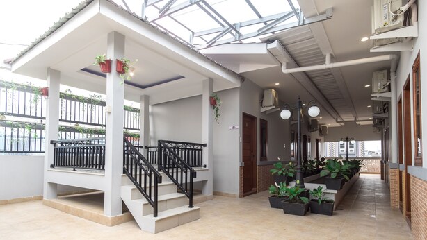Un espace extérieur abrité, doté d’un escalier, de plantes en pot et offrant une vue sur l’extérieur.