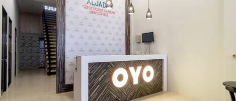 A reception area with a modern design, featuring a reception desk labeled "OYO" and a wall with the "ALJAD" logo.
