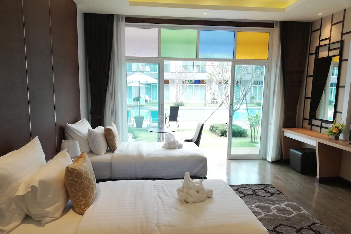Een hotelkamer met twee bedden, een bureau en uitzicht op het buitengebied.