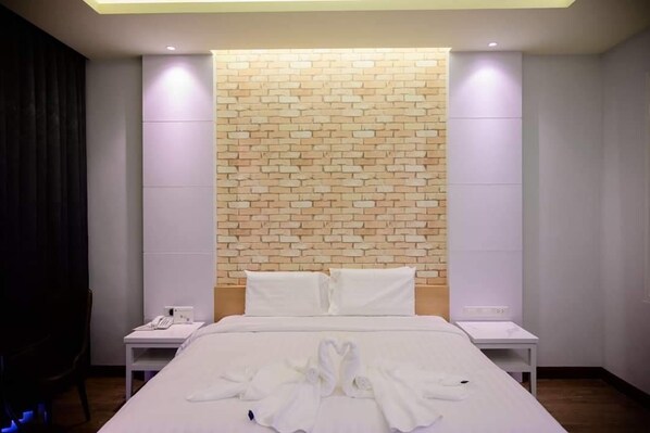 A hotel room with a brick-patterned accent wall, a neatly made bed, and two bedside tables with lamps.