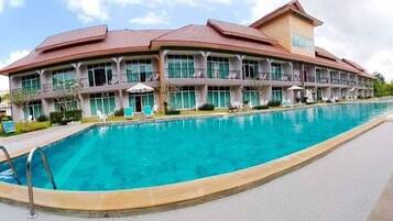 A hotel with a large swimming pool, multiple balconies, and a modern architectural design.